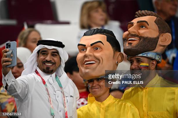 Football fan takes a selfie photo with supporters wearing masks of Portugal forward Cristiano Ronaldo and Argentina forward Lionel Messi prior to the...