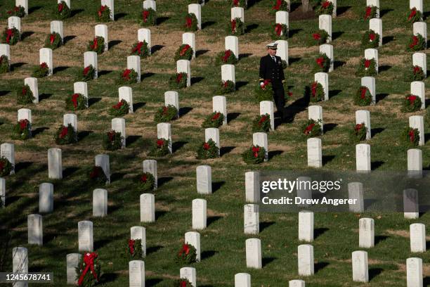 Volunteers place wreaths on headstones at Arlington National Cemetery on December 17, 2022 in Arlington, Virginia. Thousands of volunteers...