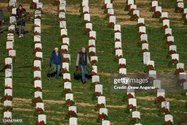 Volunteers place wreaths on headstones at Arlington National Cemetery on December 17, 2022 in Arlington, Virginia. Thousands of volunteers...