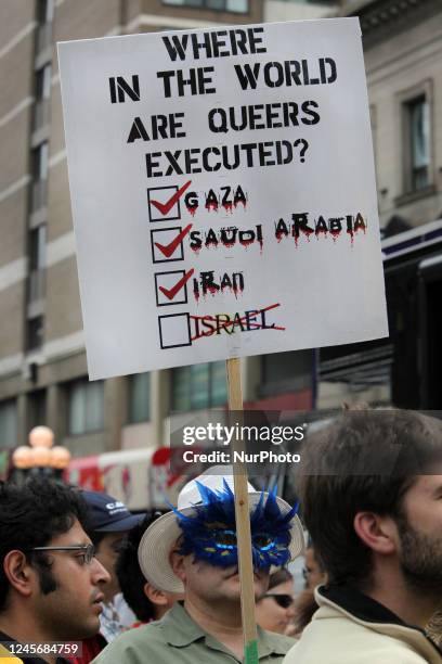 Man holds a sign protesting the treatment of gays in the Middle East during Gay Pride Week in Toronto, Ontario, Canada.