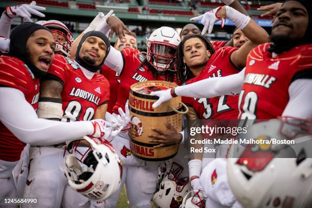 Louisville Cardinals players react with the Keg of Nails Trophy after beating the Cincinnati Bearcats in the 2022 Wasabi Fenway Bowl on December 17,...