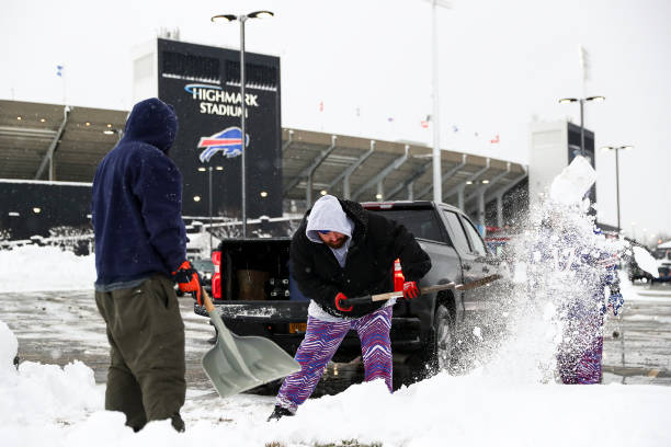 Buffalo Bills fans shovel snow outside of Highmark Stadium prior to an NFL football game between the Miami Dolphins and the Buffalo Bills on December...