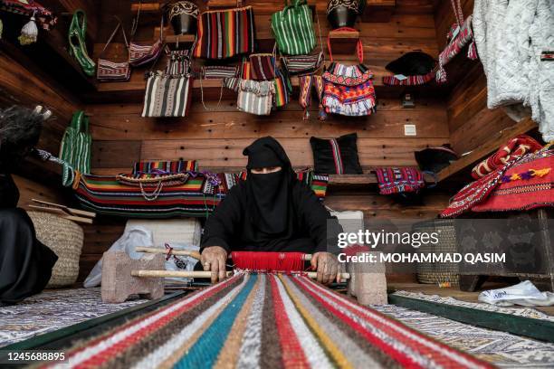 Women operate traditional weaving looms in the old town of the Khaybar oasis in northwestern Saudi Arabia on December 12, 2022. - Khaybar, best known...