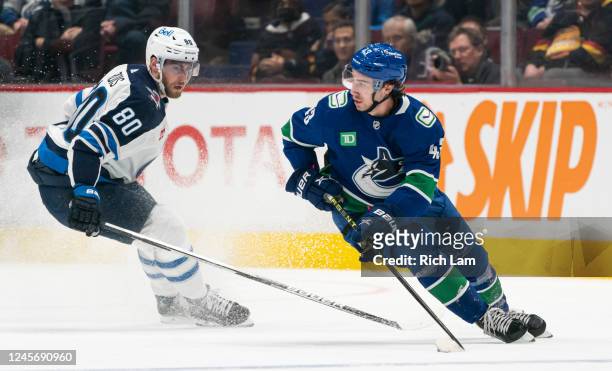 Quinn Hughes of the Vancouver Canucks looks to make a pass while being pursued by by Pierre-Luc Dubois of the Winnipeg Jets during the first period...