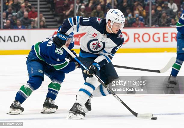 Cole Perfetti of the Winnipeg Jets tries to break free from the check of Conor Garland of the Vancouver Canucks during the first period of NHL action...