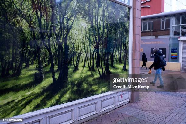 People passing a beautiful image of nature painted in a picture of a woodland in an empty window on 16th December 2022 in Birmingham, United Kingdom.