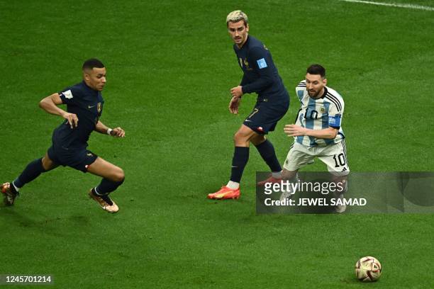 Argentina's forward Lionel Messi fights for the ball with France's forward Antoine Griezmann and France's forward Kylian Mbappe during the Qatar 2022...