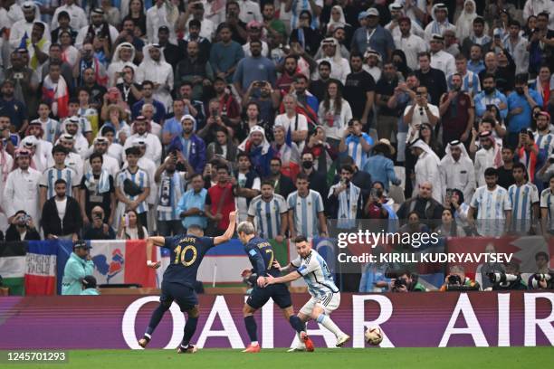 France's forward Kylian Mbappe and France's forward Antoine Griezmann fight for the ball with Argentina's forward Lionel Messi during the Qatar 2022...