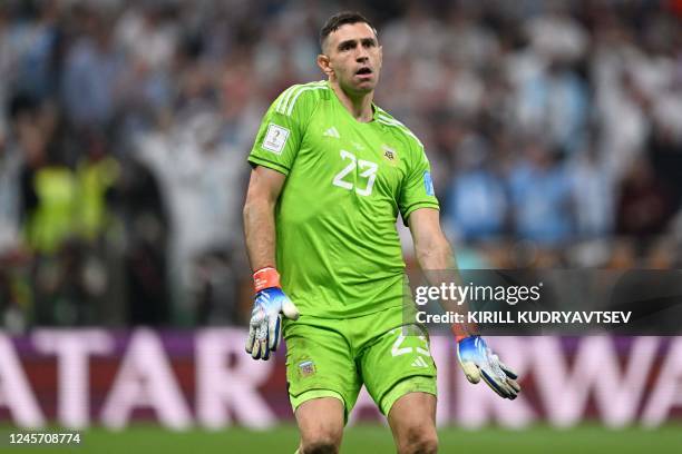 Argentina's goalkeeper Emiliano Martinez celebrates after his team scored in the penalty shootout during the Qatar 2022 World Cup final football...