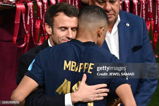 French President Emmanuel Macron hugs France's forward Kylian Mbappe at the end of the Qatar 2022 World Cup final football match between Argentina...