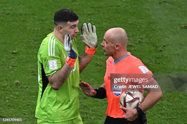 Polish referee Szymon Marciniak shows a shows a yellow card to Argentina's goalkeeper Emiliano Martinez during the Qatar 2022 World Cup final...