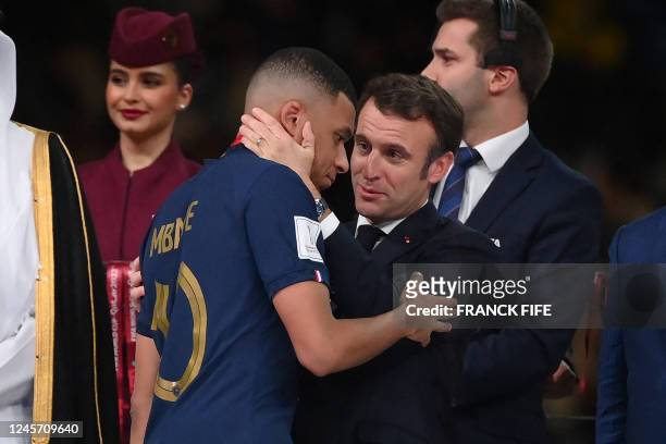 France's forward Kylian Mbappe is greeted by French President Emmanuel Macron on the podium after receiving the silver medal during the Qatar 2022...