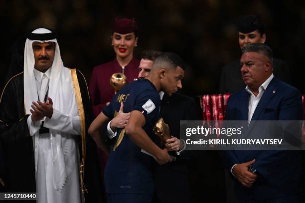 France's forward Kylian Mbappe is consoled by French President Emmanuel Macron next to Qatar's Emir Sheikh Tamim bin Hamad al-Thani after he received...