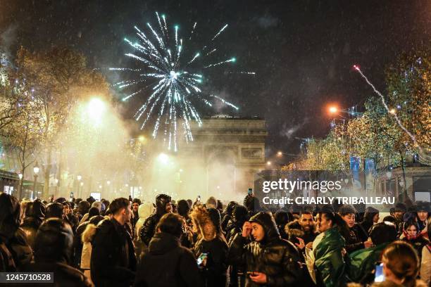 Fireworks explode overhead as people gather on the Champs-Elysees after the final football match of the Qatar 2022 World Cup between Argentina and...