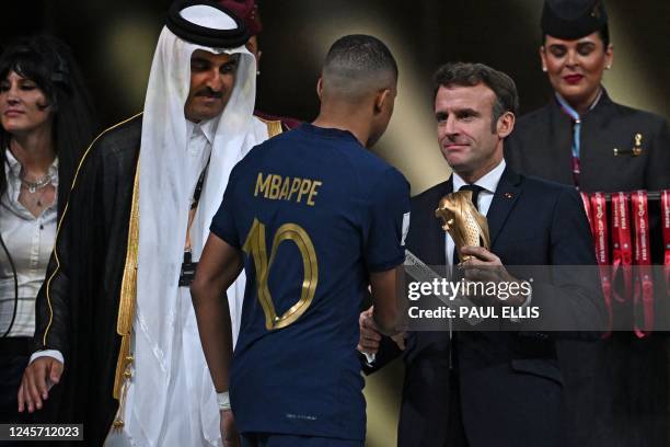France's forward Kylian Mbappe receives the Golden Boot award from French President Emmanuel Macron next to Qatar's Emir Sheikh Tamim bin Hamad...