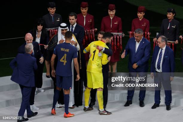 France's goalkeeper Hugo Lloris is greeted by French President Emmanuel Macron as France's defender Raphael Varane receives his silver medal from the...