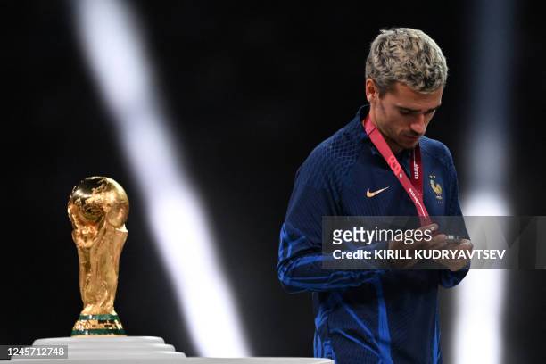France's forward Antoine Griezmann looks at his silver medal as he walks past the FIFA World Cup trophy during the trophy ceremony after France lost...