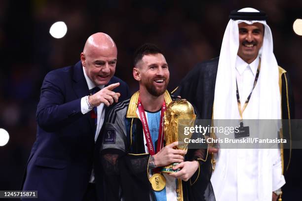 Lionel Messi of Argentina holds the FIFA World Cup Qatar 2022 Winner's Trophy watched by Gianni Infantino, President of FIFA at the end of the FIFA...