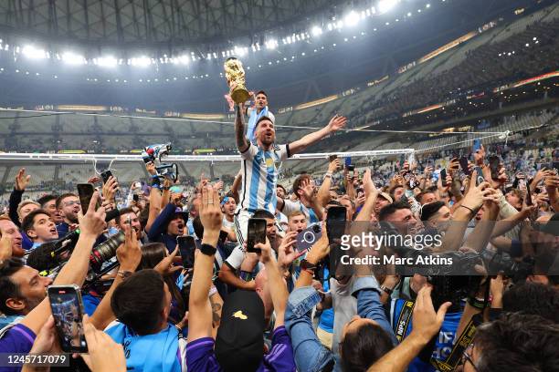 Lionel Messi of Argentina celebrates with the World Cup Trophy as he rides on the shoulders of Sergio Aguero during the FIFA World Cup Qatar 2022...