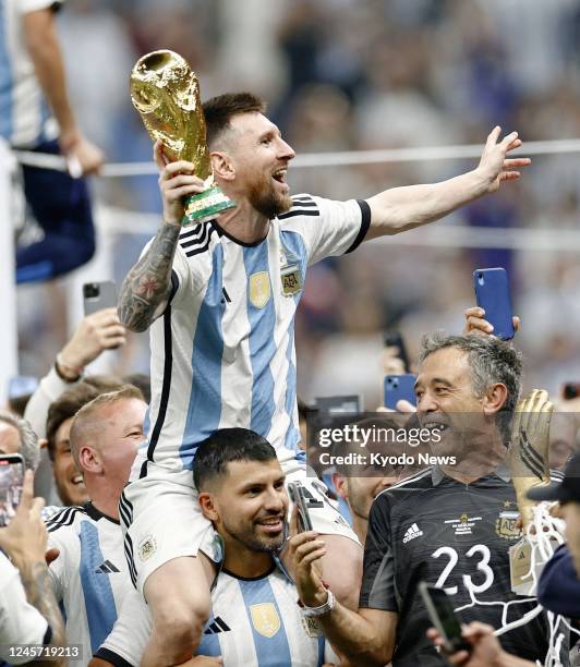 Argentina's Lionel Messi celebrates with the trophy while on the shoulders of former teammate Sergio Aguero after Argentina beat France 4-2 on...