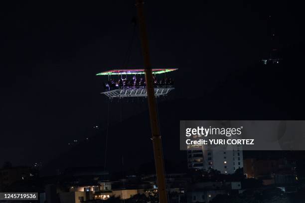 People sit at tables on a platform of the first hanging restaurant to be opened to the public in Venezuela in the Altamira neighborhood of Caracas on...
