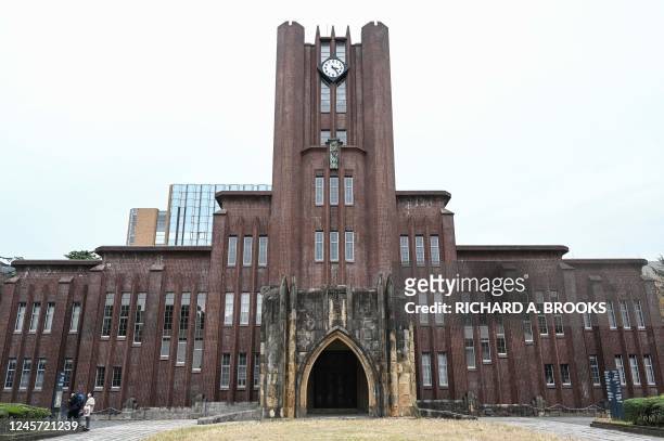This photo taken on December 17, 2022 shows people looking at a sign next to Yasuda Auditorium, build in 1925 and at the centre of the Hongo campus...