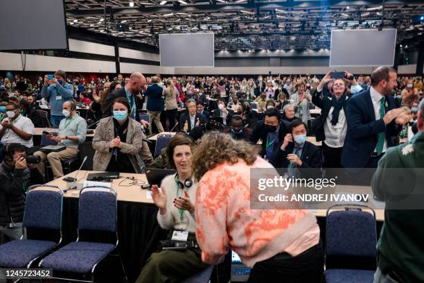 Delegates react after the agreements were adopted during the plenary for the tail end of the United Nations Biodiversity Conference in Montreal,...