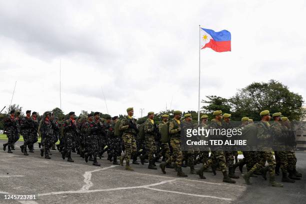 Philippine military personnel march in front of a national flag during the 87th anniversary celebration of the Armed Forces of the Philippines, at...