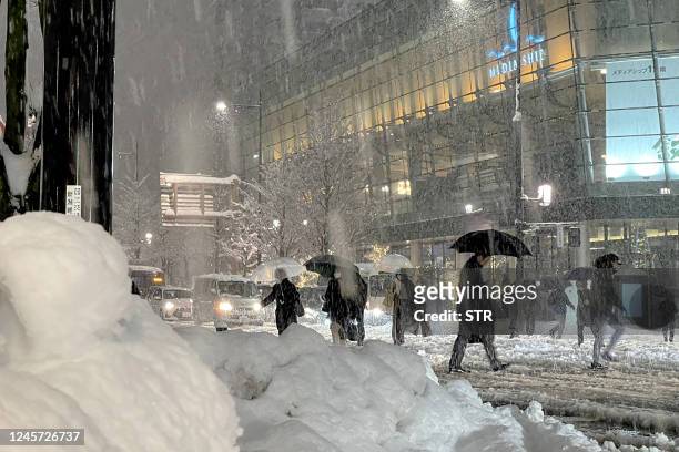 People cross the road carefully as heavy snow hits northern Japan in the city of Niigata on December 19, 2022. - Japan OUT / Japan OUT