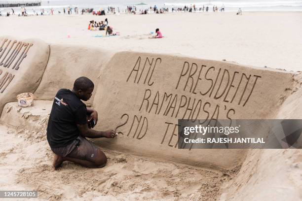 South African sand sculptor gives final touches to text reading: "ANC President Ramaphosa's second term", following the re-election of South African...