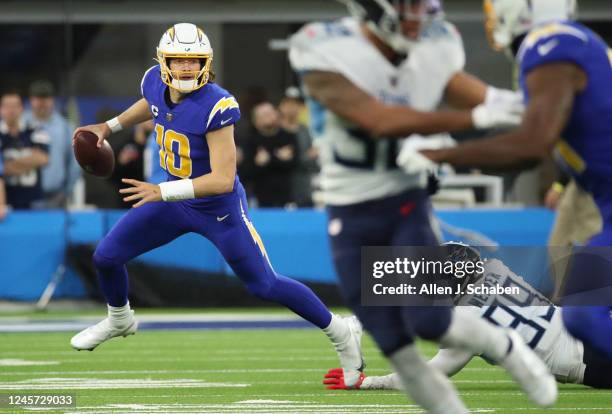Inglewood, CA Titans linebacker Rashad Weaver, right, #99, misses a tackle as Chargers quarterback Justin Herbert, #10 scrambles before passing the...