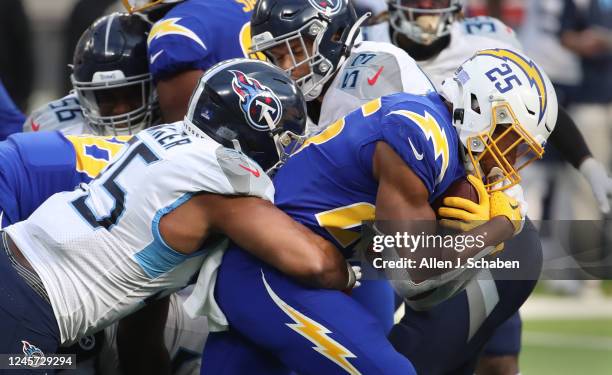 Inglewood, CA Chargers running back Joshua Kelley, right, #25, rushes as Titans defensive lineman DeMarcus Walker, left, and linebacker Dylan Cole,...