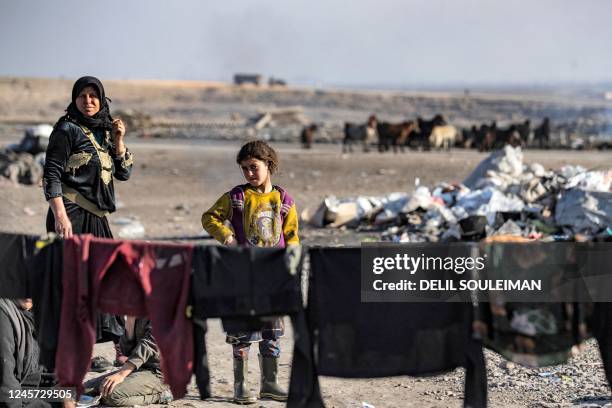 Woman and a girl stand near clothes hanging to dry on a line at a camp for those displaced by conflict in the countryside near Syria's northern city...