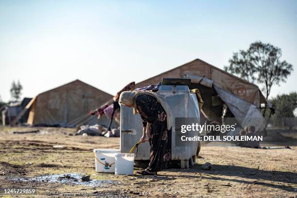Woman fills up buckets from a cistern at a camp for those displaced by conflict in the countryside near Syria's northern city of Raqa on December 19,...