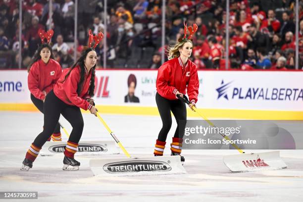 Calgary Flames ice crew members shovel snow during the first period of an NHL game between the Calgary Flames and the St. Louis Blues on December 16...