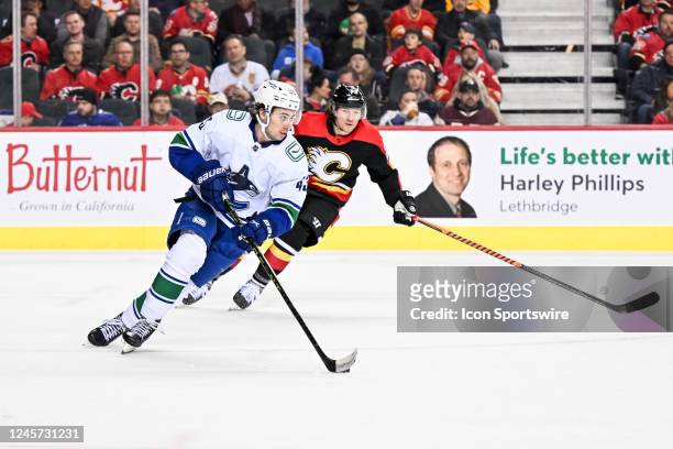 Vancouver Canucks Defenceman Quinn Hughes skates with the puck with Calgary Flames Right Wing Tyler Toffoli in pursuit during the second period of an...