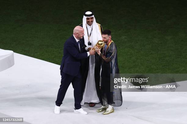 Lionel Messi of Argentina wearing a Bischt receives the FIFA World Cup trophy from the Emir of Qatar, Tamim Bin Hamad Al Thani and FIFA President...