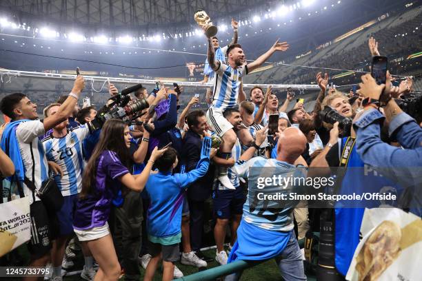 Argentina players climb the goalposts surrounded by friends and family as former player Sergio Aguero carries Lionel Messi of Argentina on his...