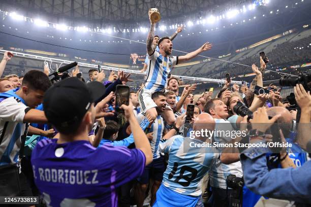 Argentina players climb the goalposts surrounded by friends and family as former player Sergio Aguero carries Lionel Messi of Argentina on his...