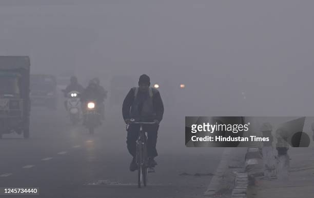 Vehicles move slowly amid low visibility due to fog on a cold winter morning, at NH24 near Akshardham Temple on December 19, 2022 in New Delhi,...