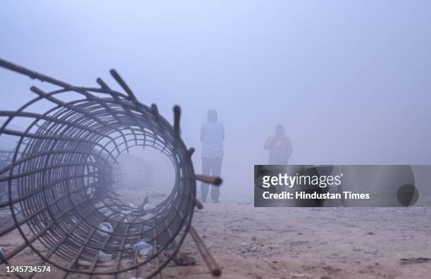People are going to work amid low visibility due to fog on a cold winter morning, at NH24 near Akshardham Temple on December 19, 2022 in New Delhi,...