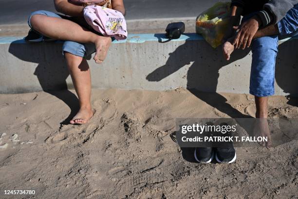 Family of migrants from Columbia dries their feet after wading through a canal and crossing under a hole in the US-Mexico border wall in El Paso,...