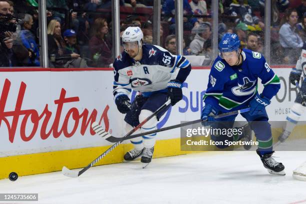 Winnipeg Jets center Mark Scheifele and Vancouver Canucks left wing Andrei Kuzmenko battle for the puck during their NHL game at Rogers Arena on...