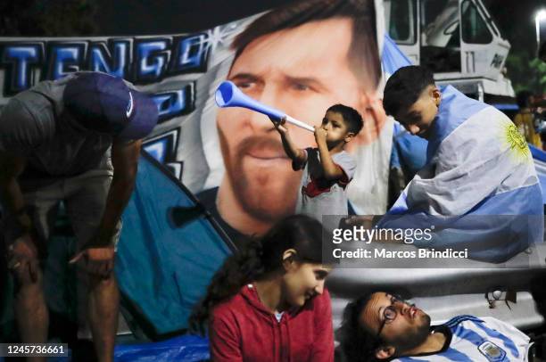 Fans wait in front of an image of Lionel Messi before the arrival of the Argentina men's national football team after winning the FIFA World Cup...