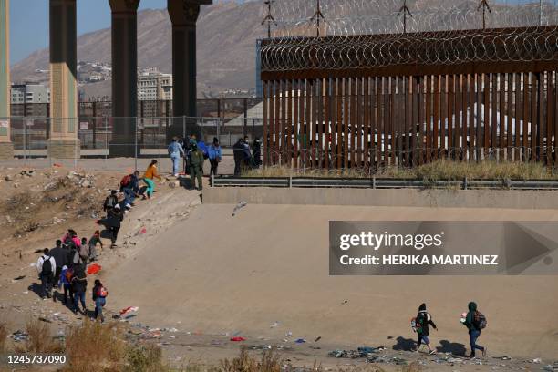 Migrants wait in line to be processed by the Border Patrol along the border wall after crossing the Rio Grande river into El Paso, Texas on the...
