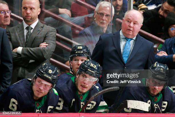 Bruce Boudreau, Brock Boeser, J.T. Miller, and Bo Horvat of the Vancouver Canucks look on from the bench during their NHL game against the St. Louis...