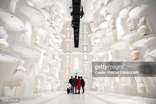 In this picture taken on December 19 guests visit the exhibition "Christian Dior: Designer of Dreams" during a media preview at the Museum of...