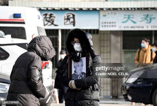 Woman holds a picture frame of a loved one at a crematorium in Beijing on December 20, 2022. - Workers at Beijing crematoriums said on December 16...