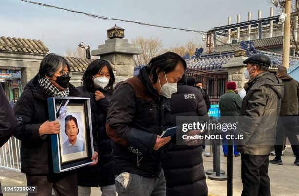 Relatives carry a picture frame of a loved at a crematorium in Beijing on December 20, 2022. - Workers at Beijing crematoriums said on December 16...