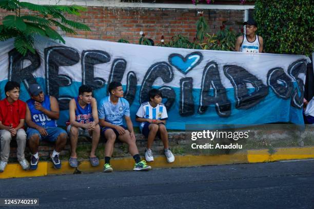 Salvadoran youth watch a game in front of a UNHCR banner of refugees from violence during soccer matches within the framework of the Street Soccer...